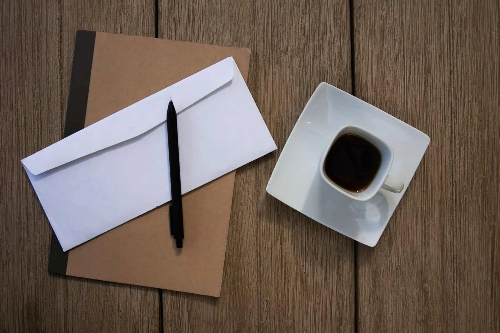 Enveloppe, carnet et tasse de café sur une table de cuisine