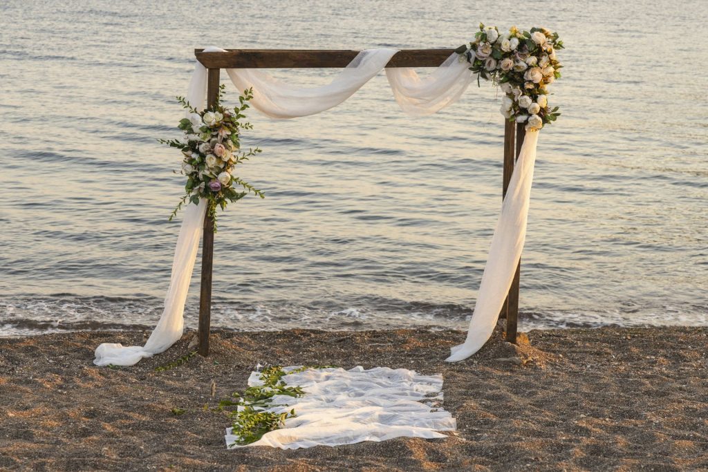 Arche de mariage fleurie sur la plage au coucher du soleil