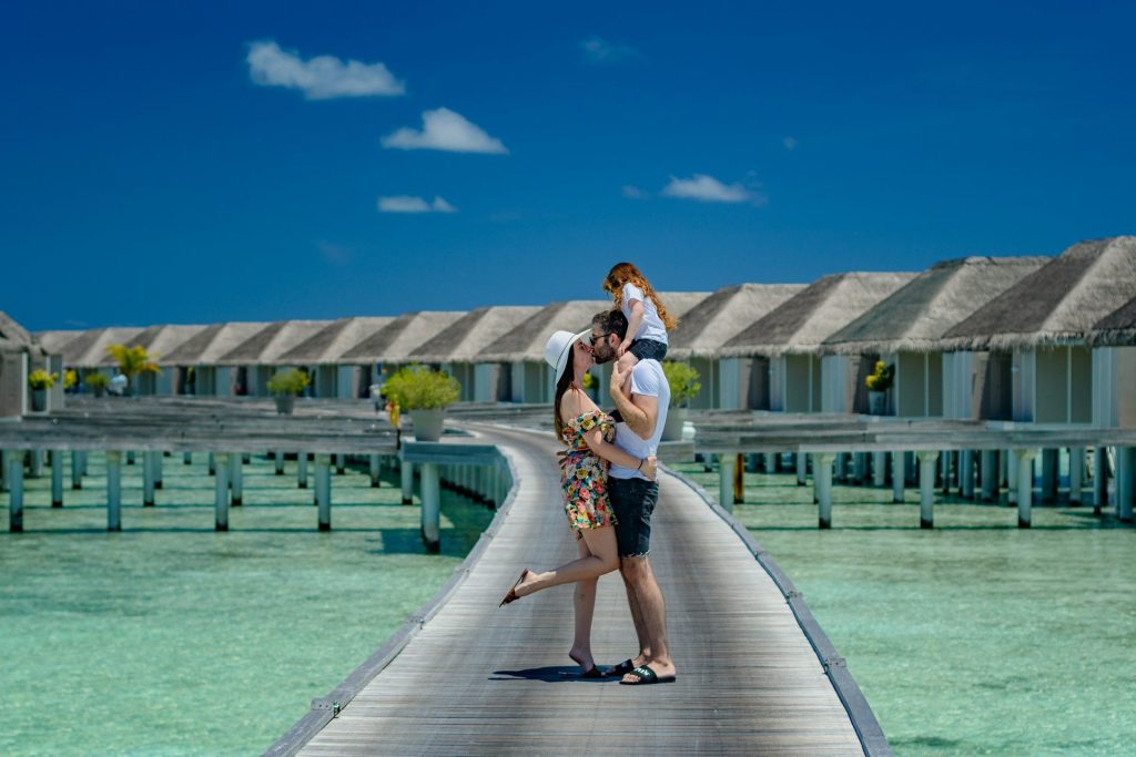 Couple enlacé sur un ponton devant des bungalows sur l’eau