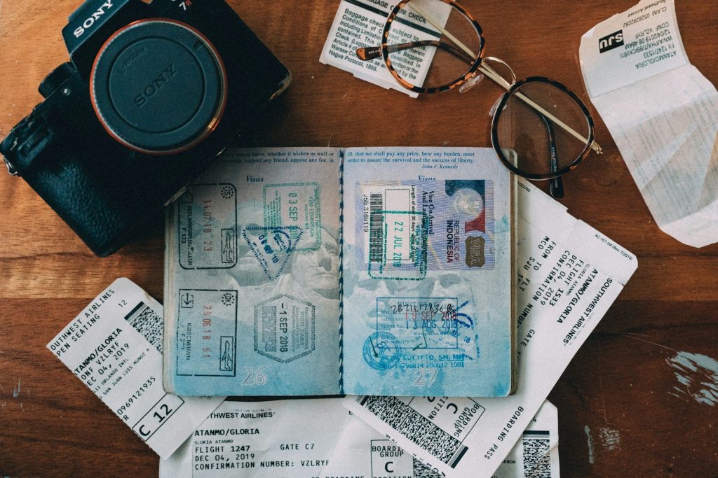 Passeport, billets et appareil photo posés à plat avant un départ