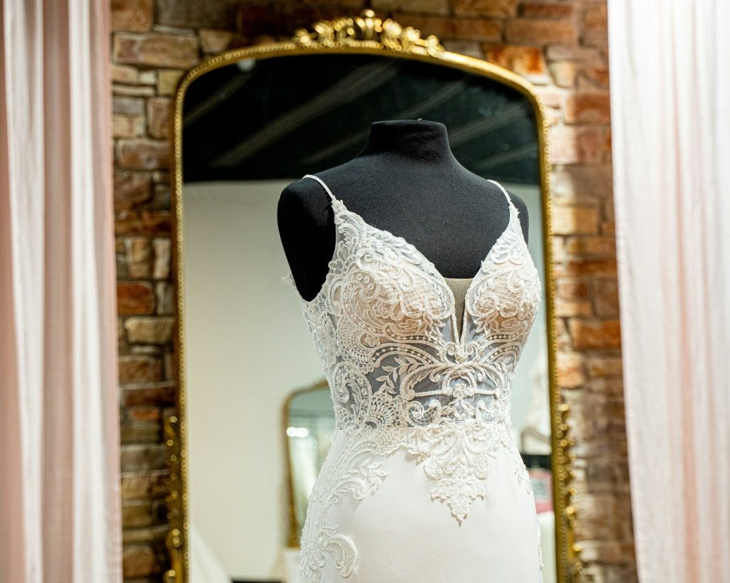 Robe de mariée en dentelle sur un mannequin devant un miroir