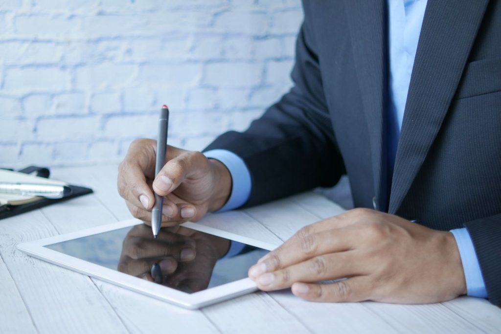 Un homme signe un document avec un stylet sur une tablette