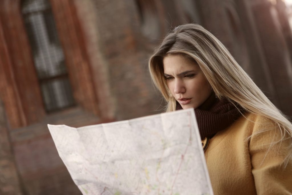 Voyageuse perplexe qui déplie un plan papier dans la rue