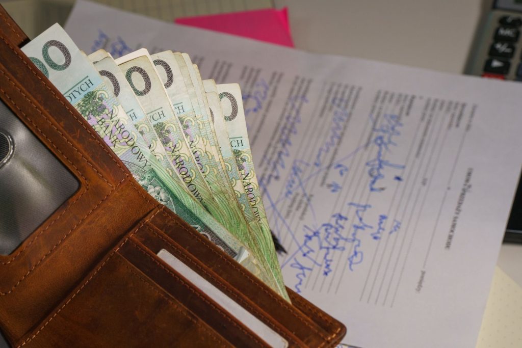 Billets en euros sortant d’un portefeuille posé sur un document