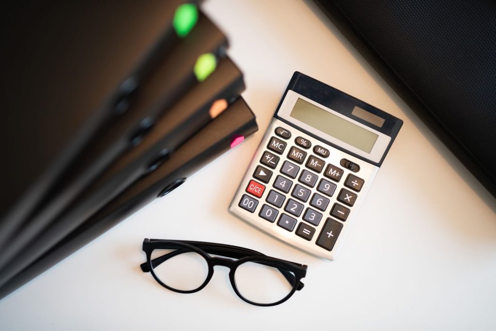 Calculatrice et lunettes posées sur des dossiers de crédit