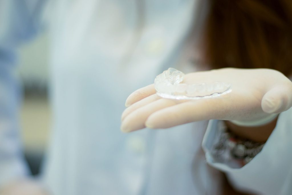 Gouttière dentaire transparente tenue dans une main gantée
