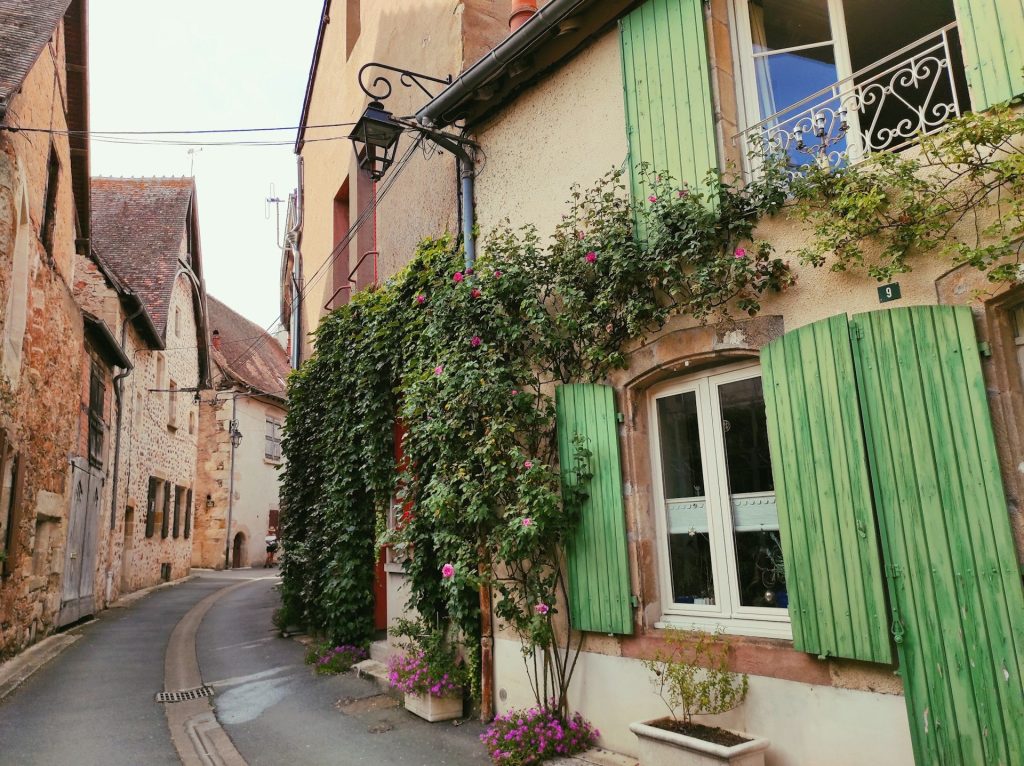 Ruelle d’un village français aux volets verts et façades de pierre
