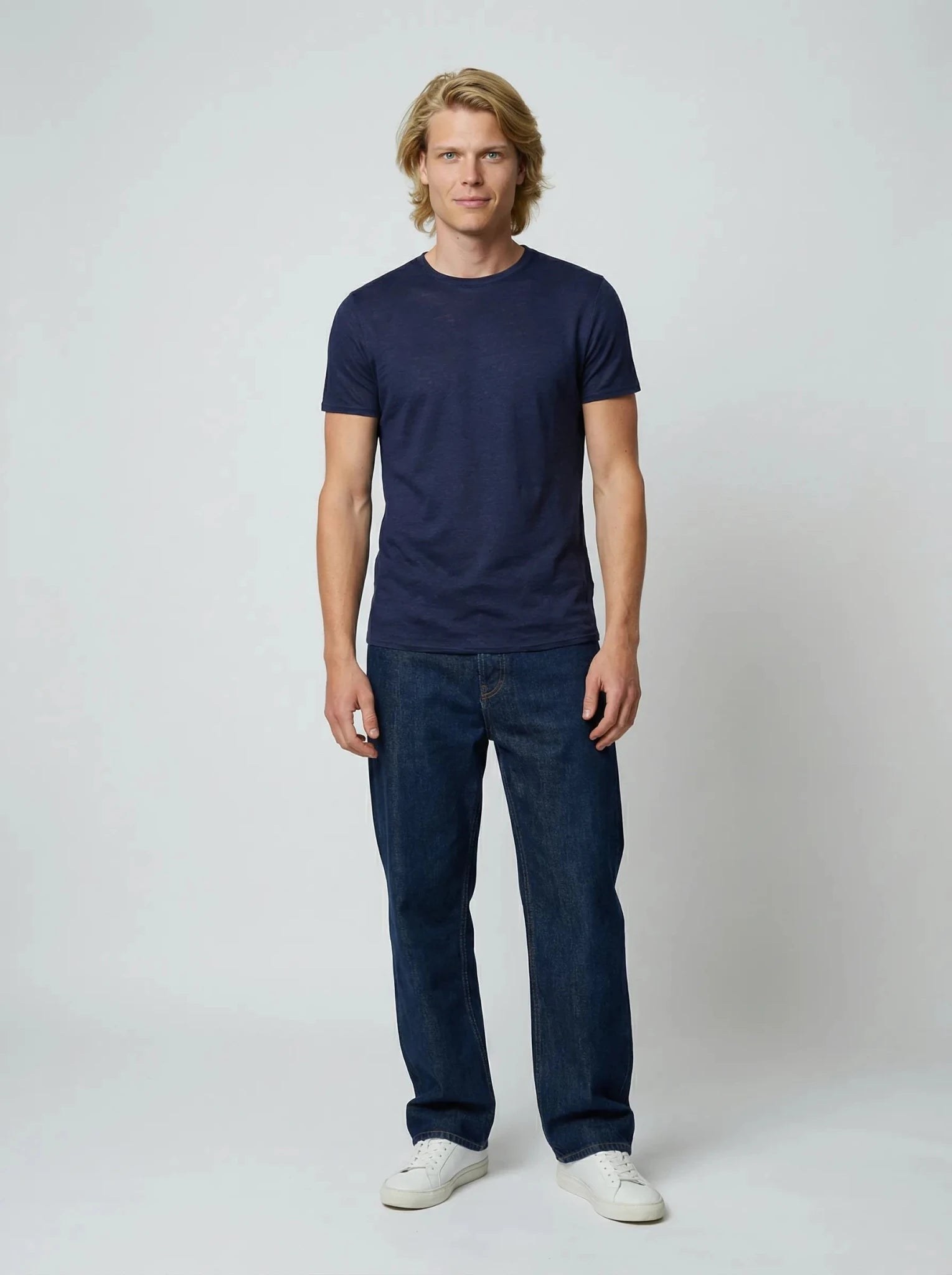 Homme en pied portant le tee-shirt en lin bleu marine avec un jean et des baskets blanches